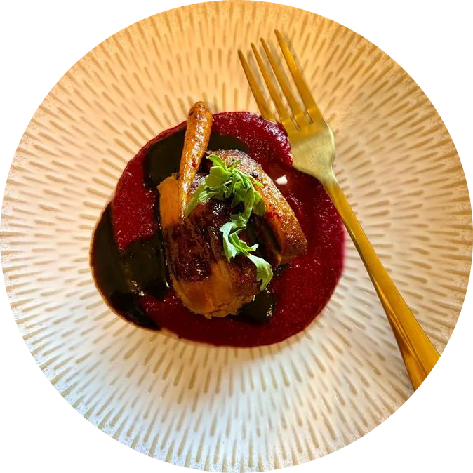 A seared fillet on beetroot purée with microgreens, a gold fork resting on a white ridged plate