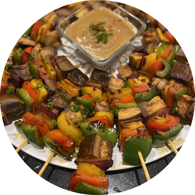 A platter of vegetable skewers around a dipping sauce